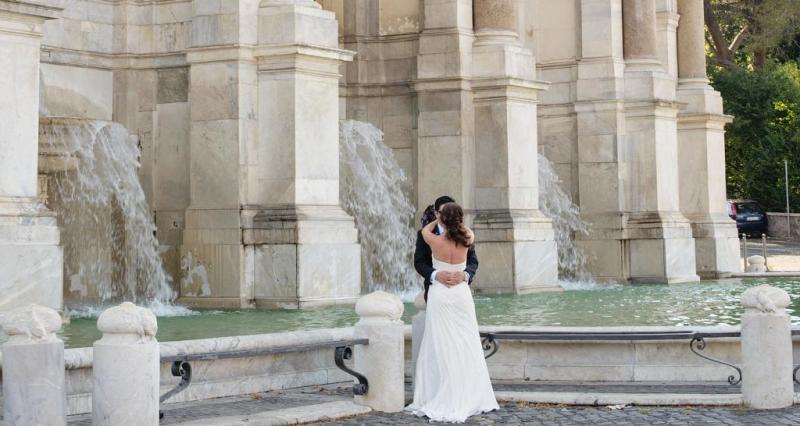 A newlywed couple kisses in front of Fontana dell'Acqua Paola during their destination wedding in Rome, Italy. 